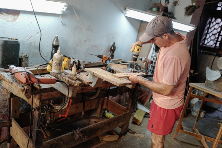 Cuban artisan Jose Miguel R. Cadalso makes parts for his wooden hand fans at his workshop in Trinidad, Sancti Spiritus province, Cuba, on June 20, 2023. - Cadalso has specialized in the production of huge wooden hand fans inspired by local religious art and visual references to utilitarian objects from the slavery era in the town of Trinidad, founded in 1514. (Photo by ADALBERTO ROQUE / AFP)