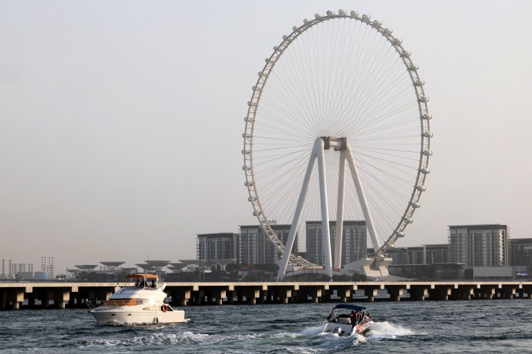 Boats cruise in the gulf waters near the Ain Dubai (Dubai Eye) observation wheel in Dubai on July 27, 2023. - Two years ago, Dubai's skyscraper-studded skyline welcomed a fresh addition: a massive ferris wheel, touted as the world's largest, but which mysteriously stopped turning only months after it was inaugurated. The so-called Ain Dubai (Dubai Eye) was intended as a tourist-luring landmark in the United Arab Emirates' glam-hub, which is also home to the world's tallest building. But now, it stands idle, its extravagant light fixtures the only parts seemingly still working. (Photo by Giuseppe CACACE / AFP)