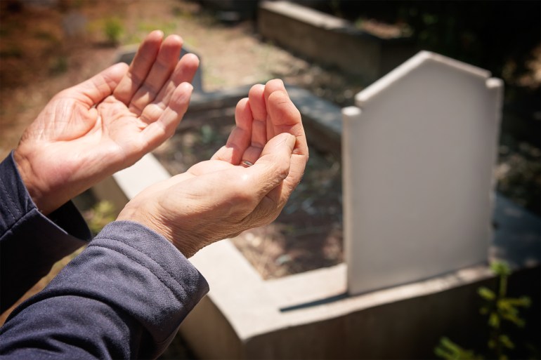 hands praying near the grave GettyImages-502396350