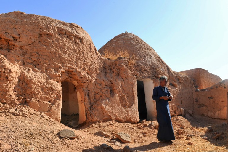 Syrian resident Mahmoud Al-Mheilij (50) inspects traditional mud-brick houses known as 'beehive houses' in the village of Umm Amuda al-Kabira in Aleppo's eastern countryside, north of Damascus on August 11, 2023. - Traditional mud houses that residents of northern Syria have built for thousands of years risk disappearing, as 12 years of war have emptied villages and left the homes crumbling. The village in Aleppo province is among a handful of villages where residents long used to live in small domed houses made of mud bricks and brittle hay. (Photo by AFP)