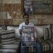 فلسطيني يحمل ملصقاً لشقيقه وابن شقيقه اللذين قُتلا في هجوم لمستوطنين بقرية كسرى قرب نابلس بالضفة الغربية يوم 12 نوفمبر الحالي (أ.ب)