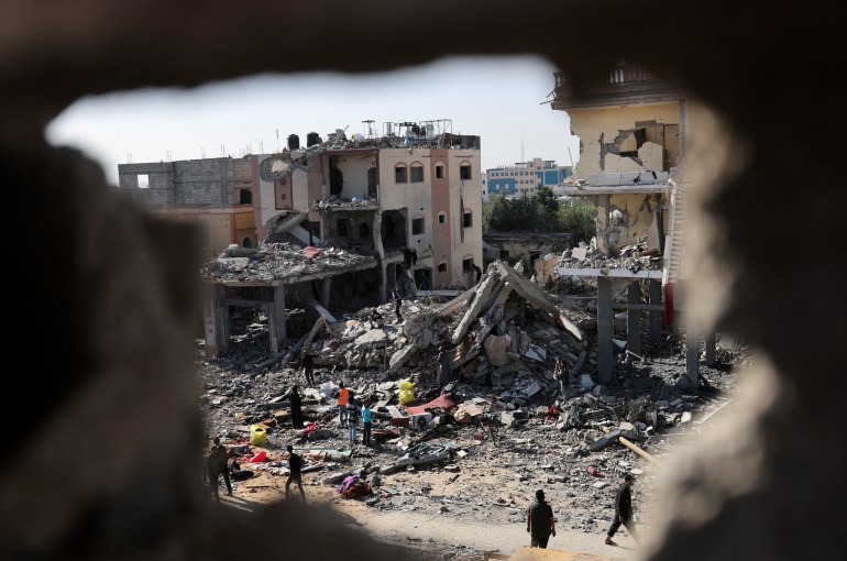 Palestinians stand among the rubble of houses destroyed in an Israeli strike during the conflict, amid the temporary truce between Hamas and Israel, in Khan Younis in the southern Gaza Strip November 24, 2023. REUTERS/Ibraheem Abu Mustafa