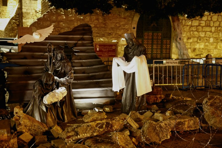 A Christmas installation of a grotto with figures standing amid rubble surrounded by a razor wire, is displayed outside the Church of the Nativity, in support of Gaza, on Manger Square in Bethlehem, in the Israeli-occupied West Bank, December 23, 2023. REUTERS/Clodagh Kilcoyne