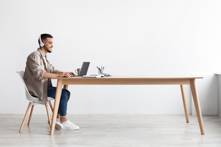 Cheerful Middle Eastern Freelancer Man Working On Pc Online At Home Listening To Music With Wireless Headphones, Making Research For New Project, Sitting At Desk Enjoying Remote Job, Profile Side View SS2142805773