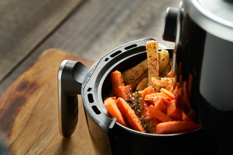 Cooking potatoes and carrot sticks with spices in an air fryer