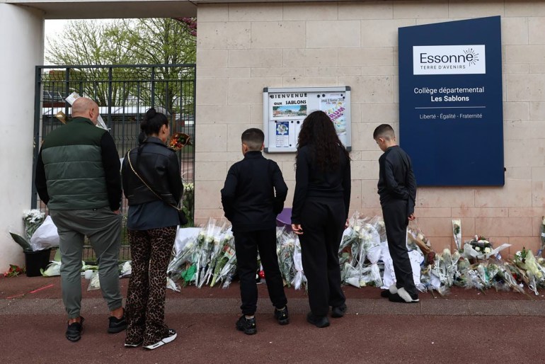 Local residents arrive to lay flowers before the entrance of middle school Les Sablons in Viry-Chatillon, on April 7, 2024, following the death of teenage boy Shamseddine, after he had been severely beaten outside the middle school on April 4, 2024. Police on April 5, 2024, detained five people linked to the attack, including three 17-year-olds, a 15-year-old and a 20-year-old, a prosecutor said. (Photo by EMMANUEL DUNAND / AFP)