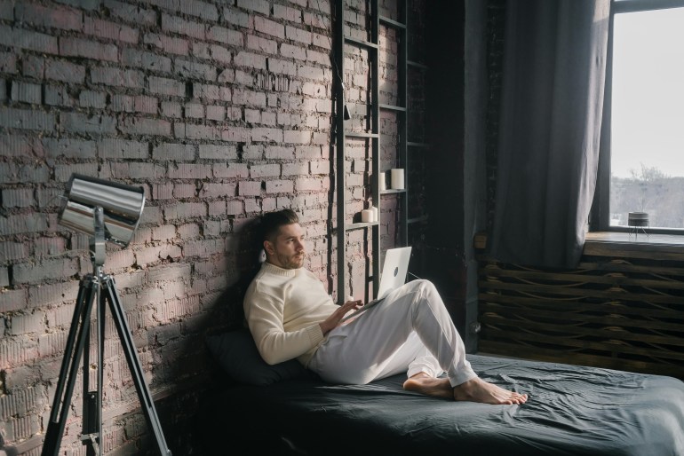 A Man Using a Laptop while Lying on the Bed