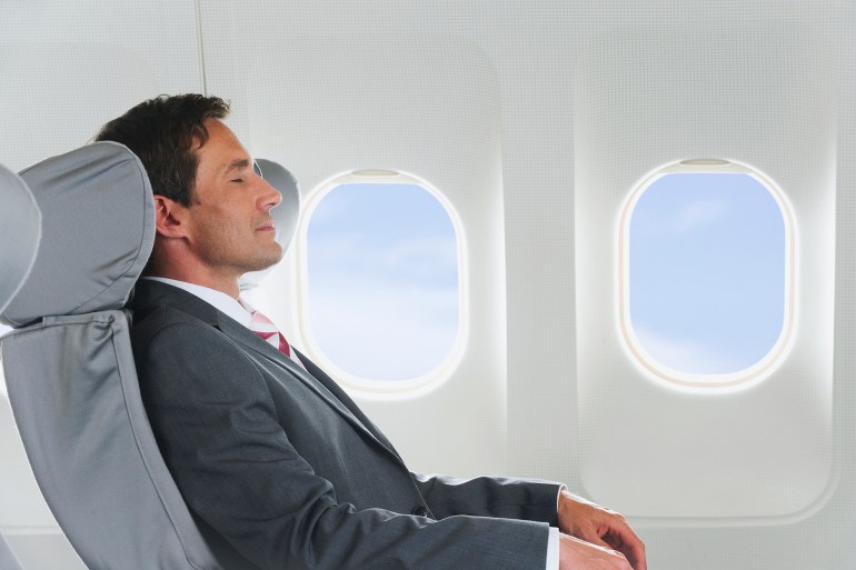 Germany, Bavaria, Munich, Mid adult businessman relaxing in business class airplane cabin - stock photo