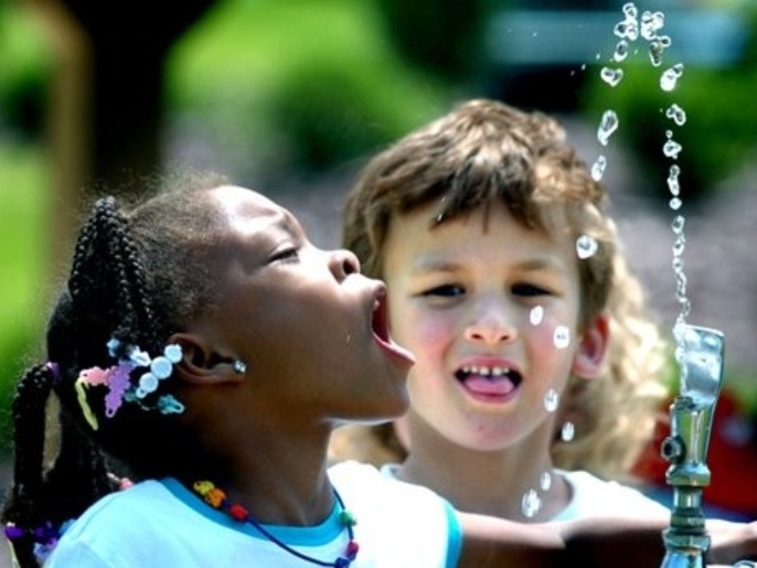 FILE - In this June 3, 2008 file photo, Liberty Valley Elementary School, Danville, Pa., kindergarten student Tianna Swisher attempts to drink from the water fountain at Montour Preserve, near Washingtonville, Pa., during the school's outdoor field trip. Fluoride in drinking water, credited with dramatically cutting cavities and tooth decay, may now be too much of a good thing. It's causing spots on some kids' teeth. A reported increase in the spotting problem is one reason the federal government will announce Friday, Jan. 7, 2011, it plans to lower the recommended limit for fluoride in water supplies, the first such change in nearly 50 years.