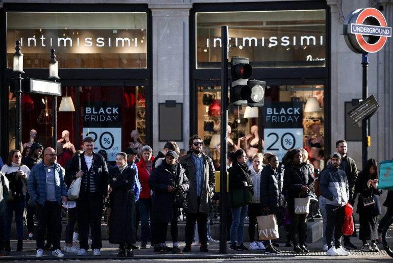 FILE PHOTO: People stand near Black Friday signage in shop windows during Black Friday on Oxford Street in London, Britain, November 25, 2022. REUTERS/Henry Nicholls/File Photo