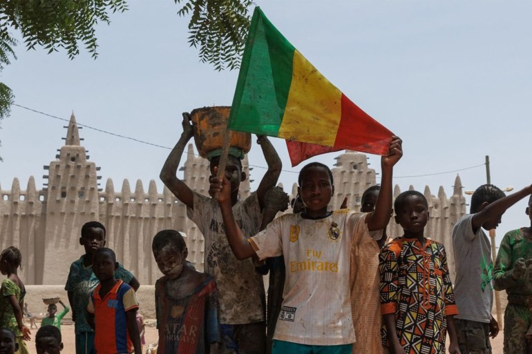 A young boy shows the Malian Nation flag during the re-plastering of the Great Mosque of Djenne in central Mali on June 3, 2023. Thousand of people from Djenne gather each year to re-plaster the walls of the Great Mosque of Djenne, which has been build from mud since 1907. (Photo by OUSMANE MAKAVELI / AFP) (Photo by OUSMANE MAKAVELI/AFP via Getty Images)