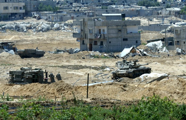 An Israeli tank takes position at Tel al-Sultan neighbourhood in the southern Gaza Strip refugee camp of Rafah 22 May 2004. A three-and-a-half-year-old Palestinian girl was shot dead in the Brazil neigborhood on day five of the Israeli army's offensive, as angry residents returned to their ruined homes after a partial withdrawal of Israeli troops. In all over 41 Palestinians have been killed in the operation. AFP PHOTO/Ahmad KHATIB/POOL (Photo by POOL / AFP)