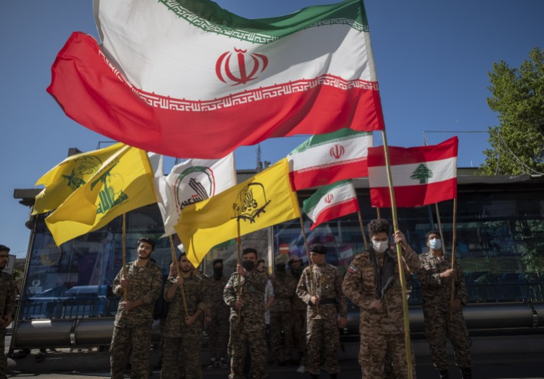 Members of the Basij paramilitary force hold Iranian flag, Lebanese flag, flag of Hashd Shabi, flag of Quds force's Fatemiyoun Brigade, and a flag of Lebanon's Hezbollah, during a rally commemorating International Quds Day, also known as the Jerusalem day, in downtown Tehran, April 14, 2023.