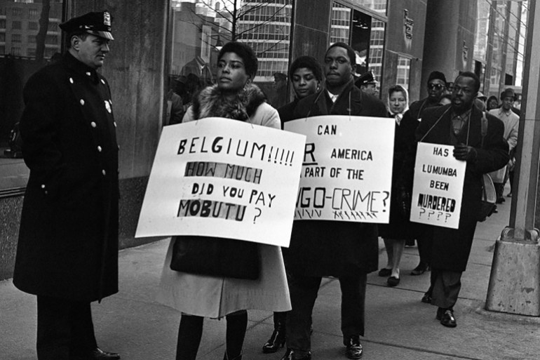 Picketers carrying anti-Belgian and pro-Lumumba placards parade on New York’s West 51st Street outside The Associated Press Building on February 11, 1961, after Lumumba was killed but news of his death had not yet been released [File: Jacob Harris/AP Photo]