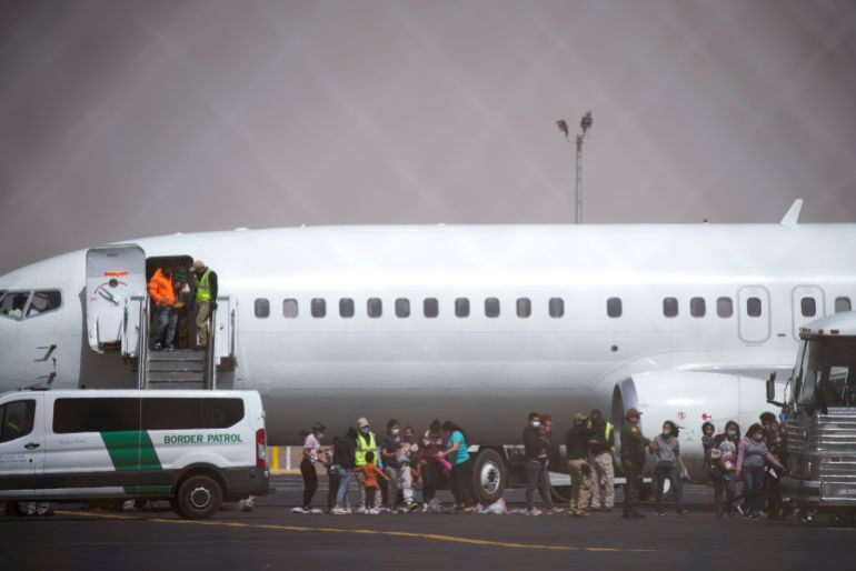 Migrants leave a chartered flight that arrived from Brownsville, Texas in the Rio Grande Valley, while en route to be deported to Juarez, Mexico, at El Paso International Airport in El Paso, Texas, U.S. March 16, 2021. Picture taken through a fence. REUTERS/Paul Ratje